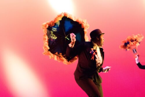 Dancer holding decorated umbrella against pink background