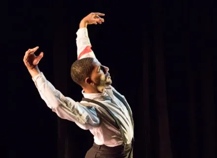 A dancers holds his arms above his head