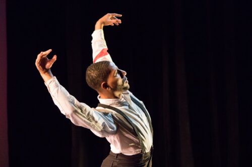 A dancers holds his arms above his head