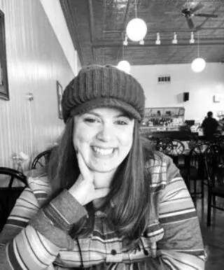 Black and white photo of Natalie smiling, with a hat on