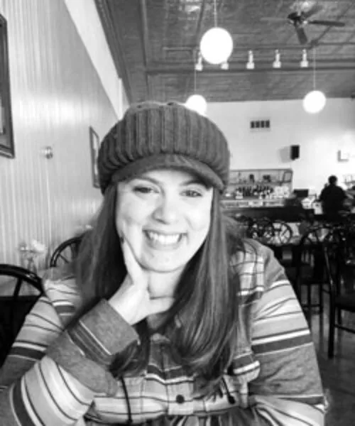 Black and white photo of Natalie smiling, with a hat on