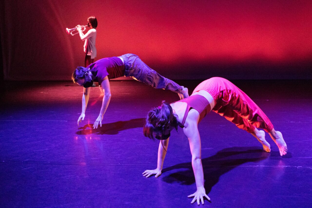 trumpet player playing as two dancers roll thru the air