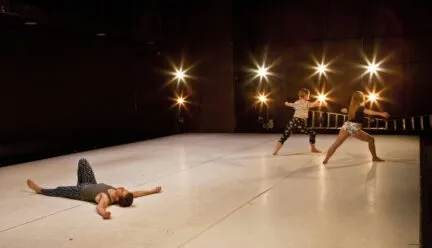 dancer on the floor with two other dancers standing in the corner