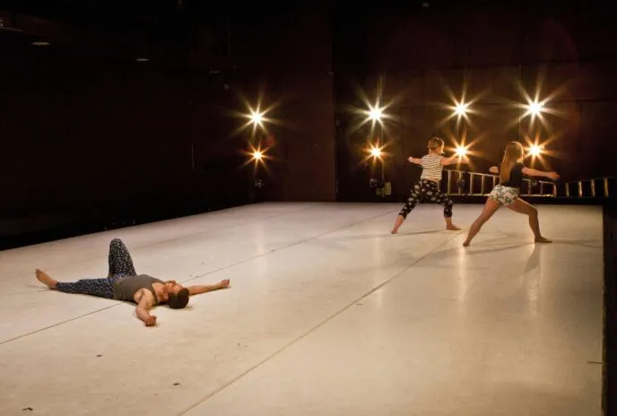 dancer on the floor with two other dancers standing in the corner