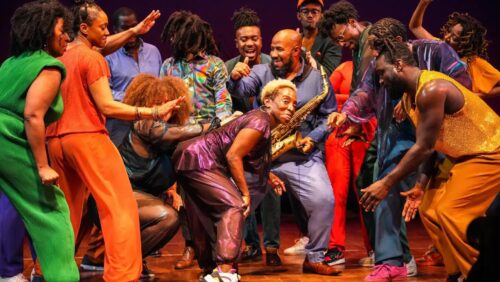 LaTasha surrounded by dancers in colorful clothes