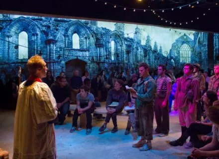 Production photo of priest addressing soldiers 