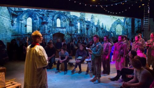 Production photo of priest addressing soldiers 