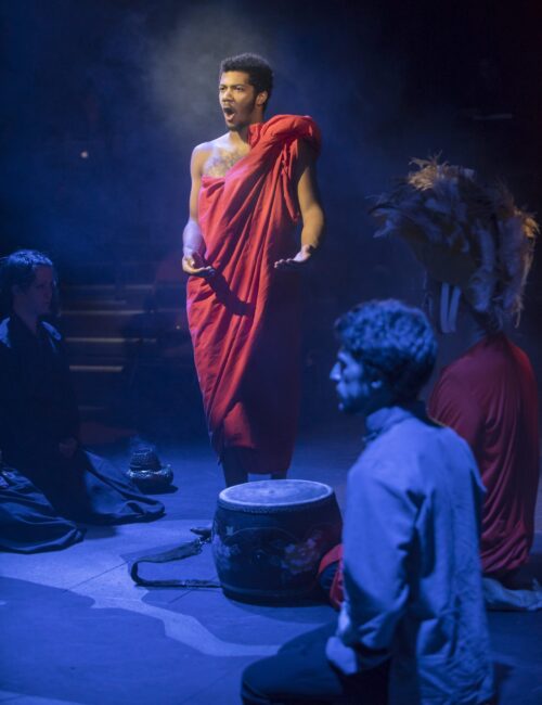 Person in toga standing in shaft of light during theatre production