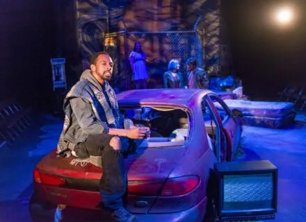 Young person sitting on trunk of car in Studio Theatre production