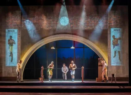 A scene from The Royale at Illinois Theatre shows the stage with 4 actors and lots of lights and scenery element