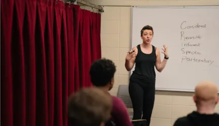 jessica steinrock stands in front of whiteboard in a classroom at Krannert Center teaching students about consent in theatre, film, and television