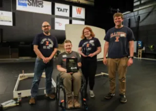 fours students wearing Illinois shirts and holding a plaque prize