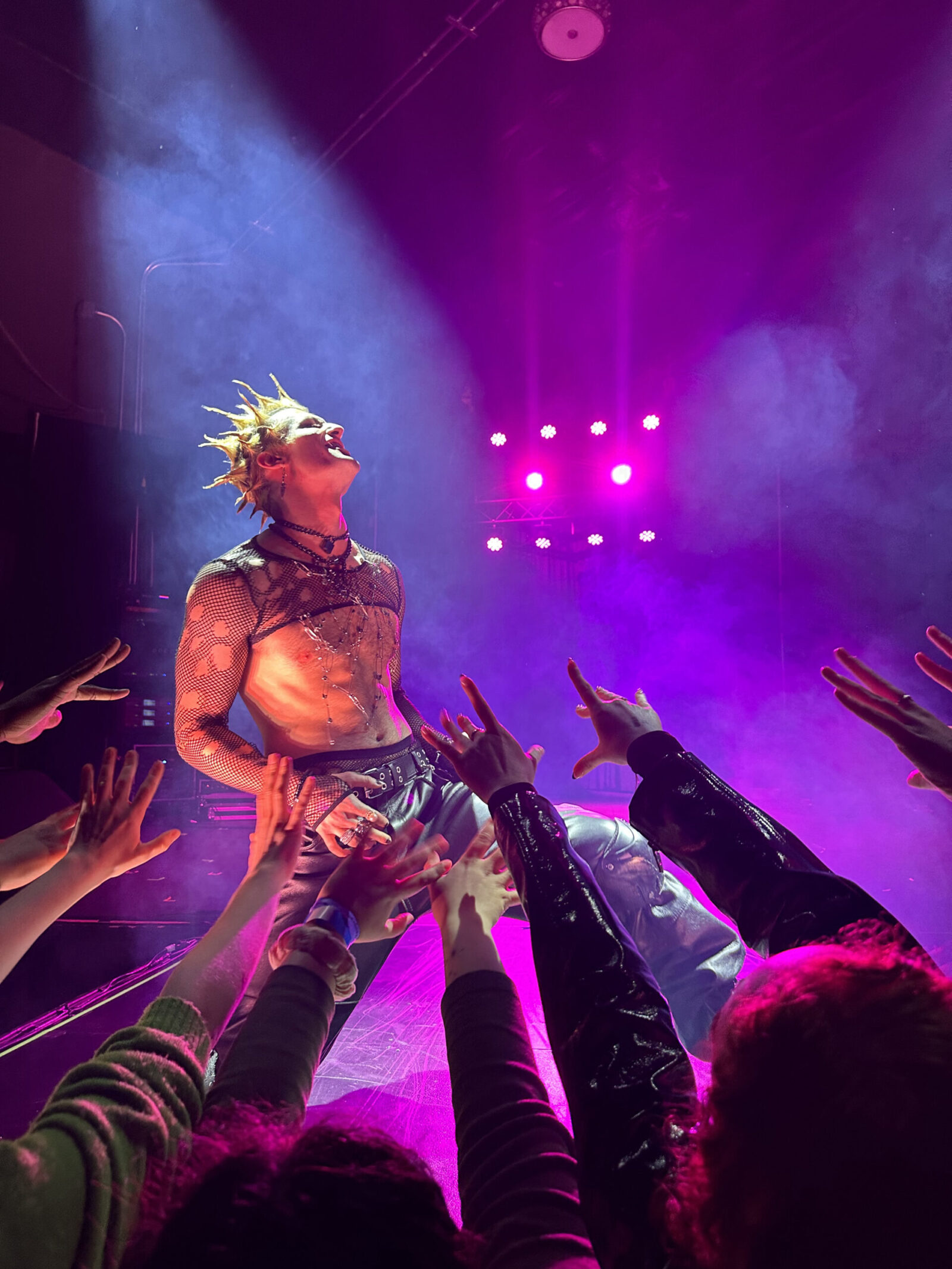 actor with spikey hair and leather pants under pink and blue lights