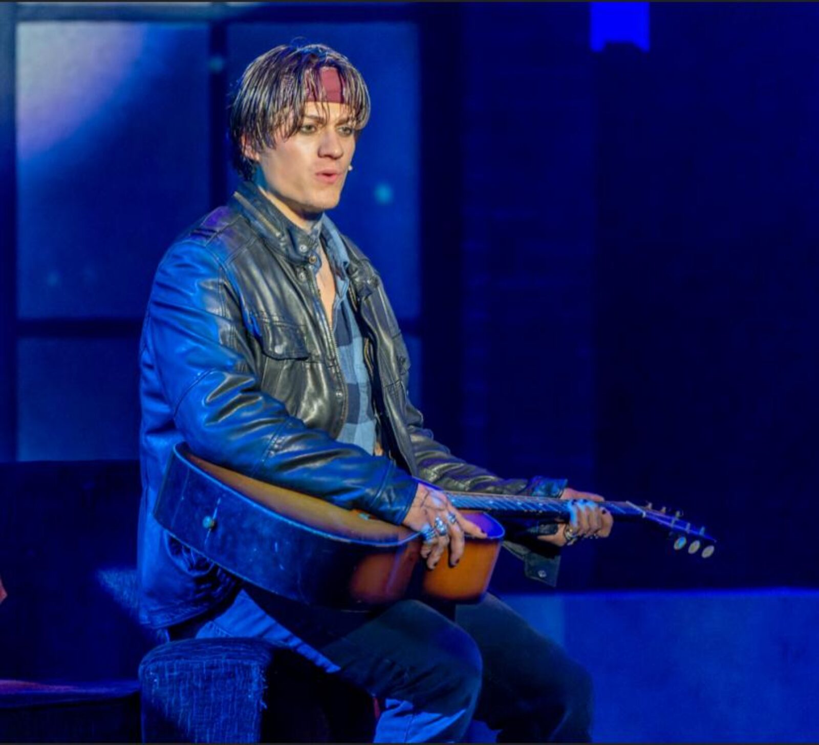 person onstage singing with guitar