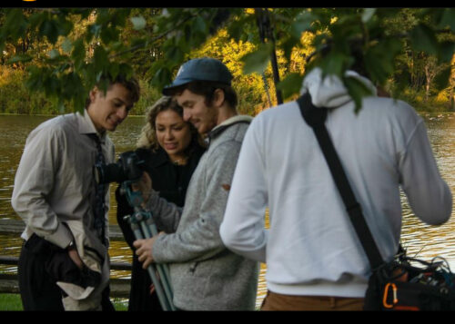 several people with filming equipment by a lake