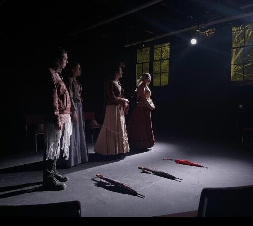 four people on stage with umbrellas 