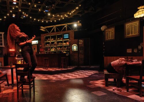 person dances onstage in dark bar setting