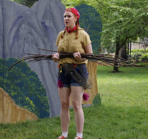 person outdoors with painted backdrop holding several pieces of wood