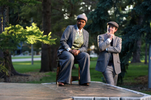 2 people outdoors in costume suits looking out
