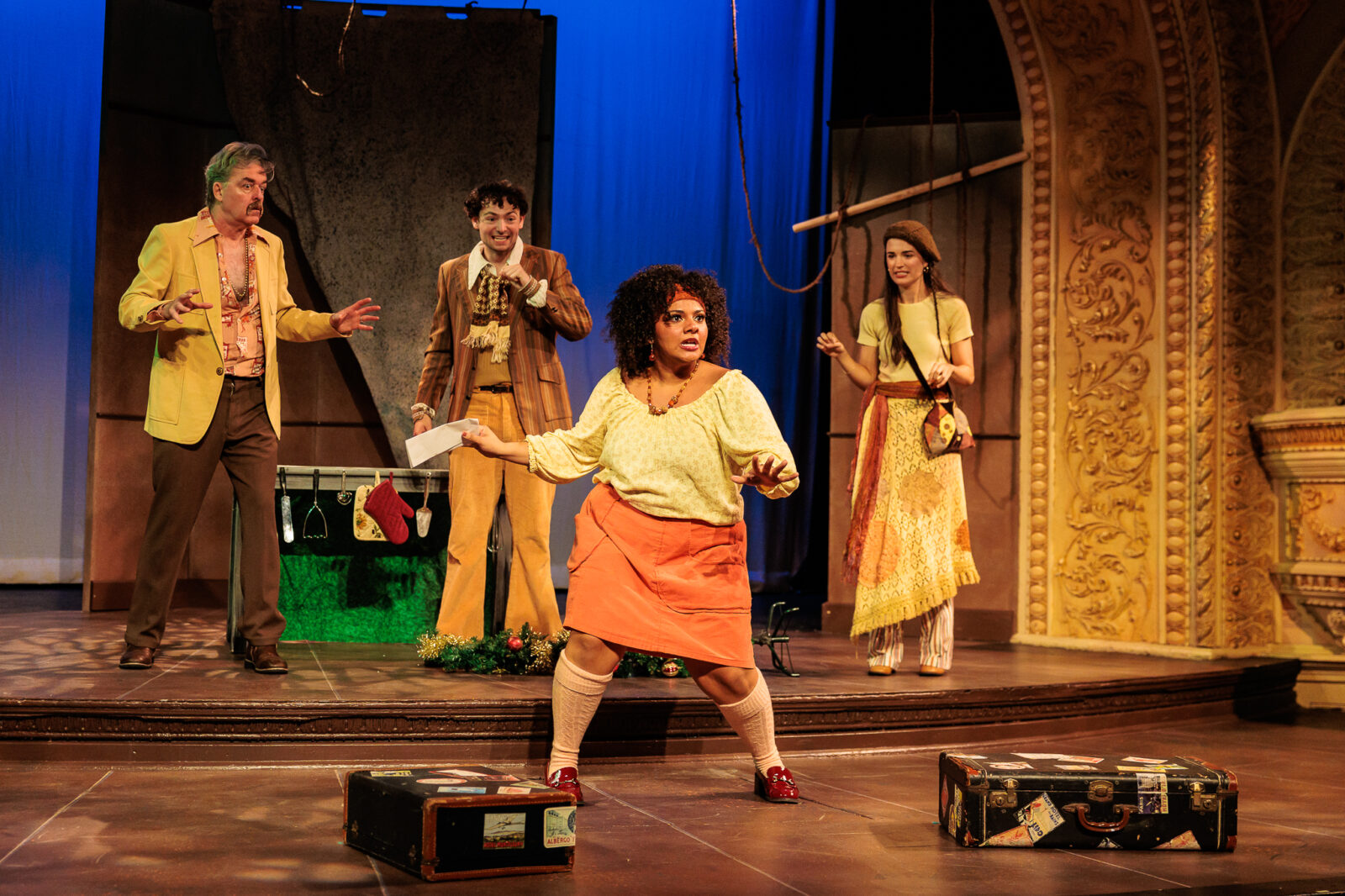 several people onstage with suitcases dancing