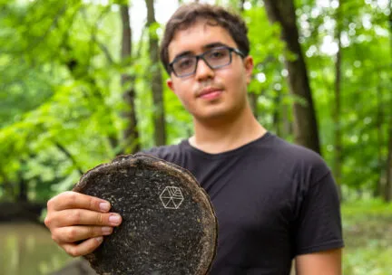 guy in forest holding up brown earthy disc