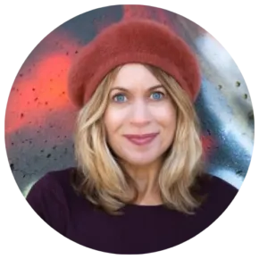 person with orange hat looks at camera standing in front of colorful wall