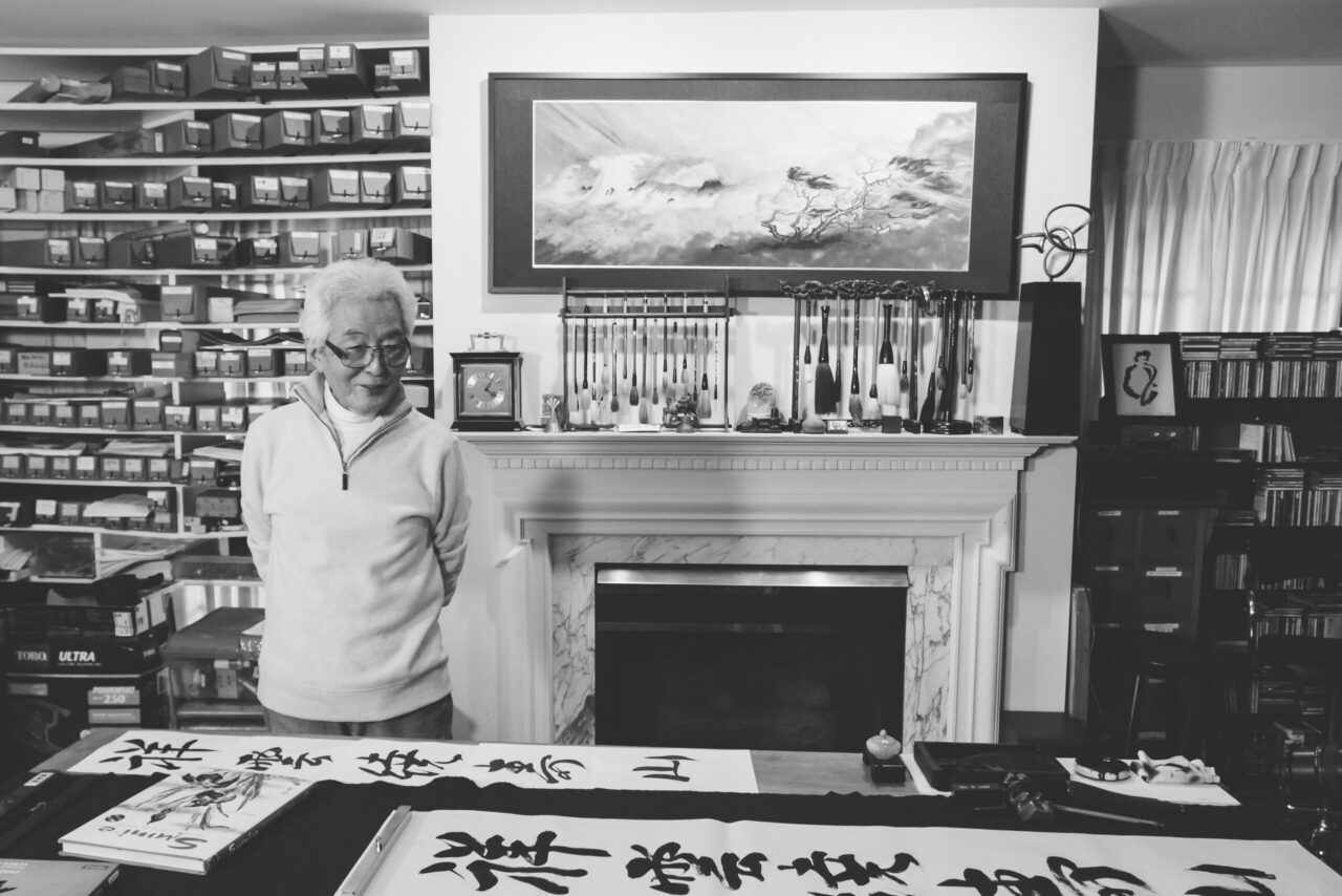 Shozo Sato in front of fireplace