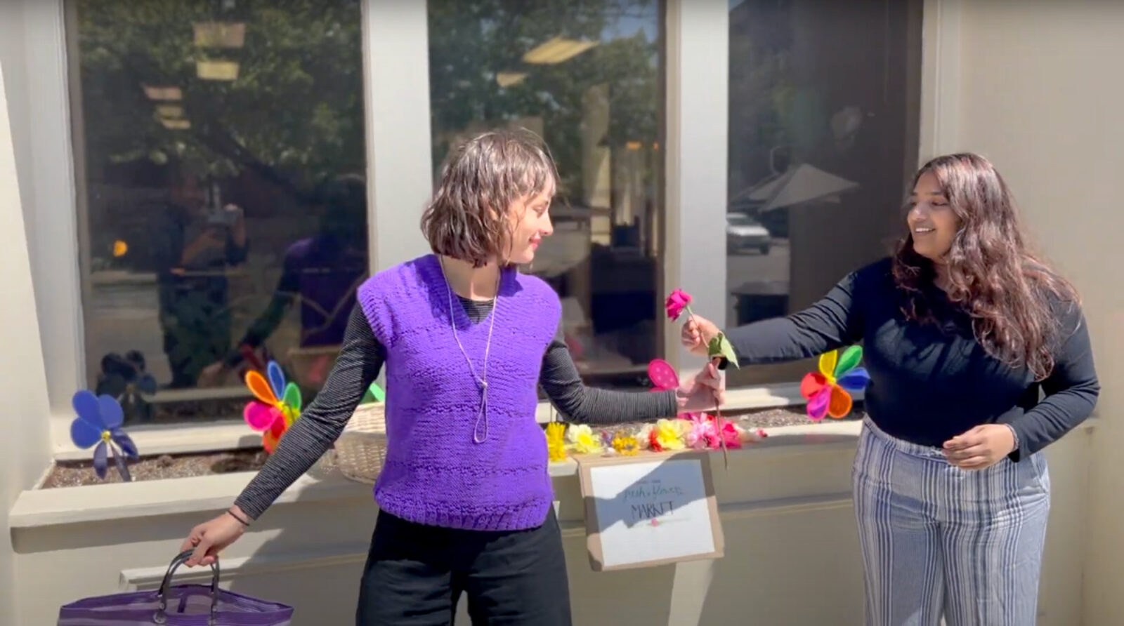 two people hand each other flowers outdoors