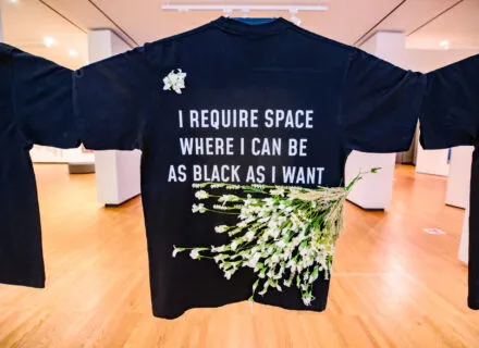black shirt with white writing and flowers attached