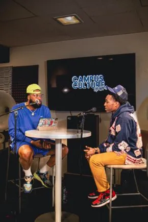 two people sitting at table talking into mics