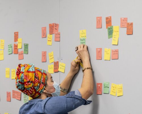 a person pins colorful sticky notes on a board