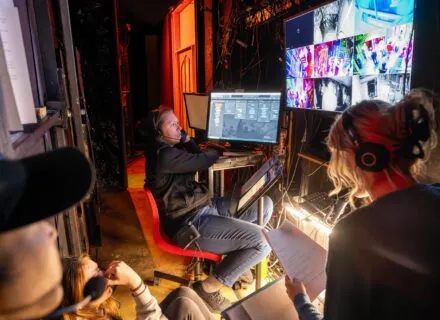 several people in a room wearing headphones and watching screens