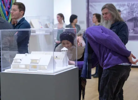 people looking at a case with a model in art museum