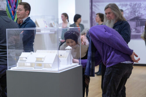 people looking at a case with a model in art museum